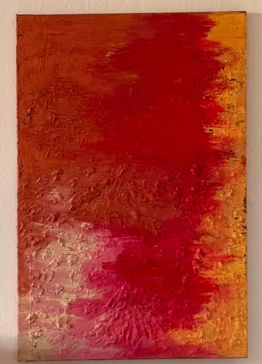 One of In&egrave;s&rsquo;s paintings: red, coral and gold, on the wall at home